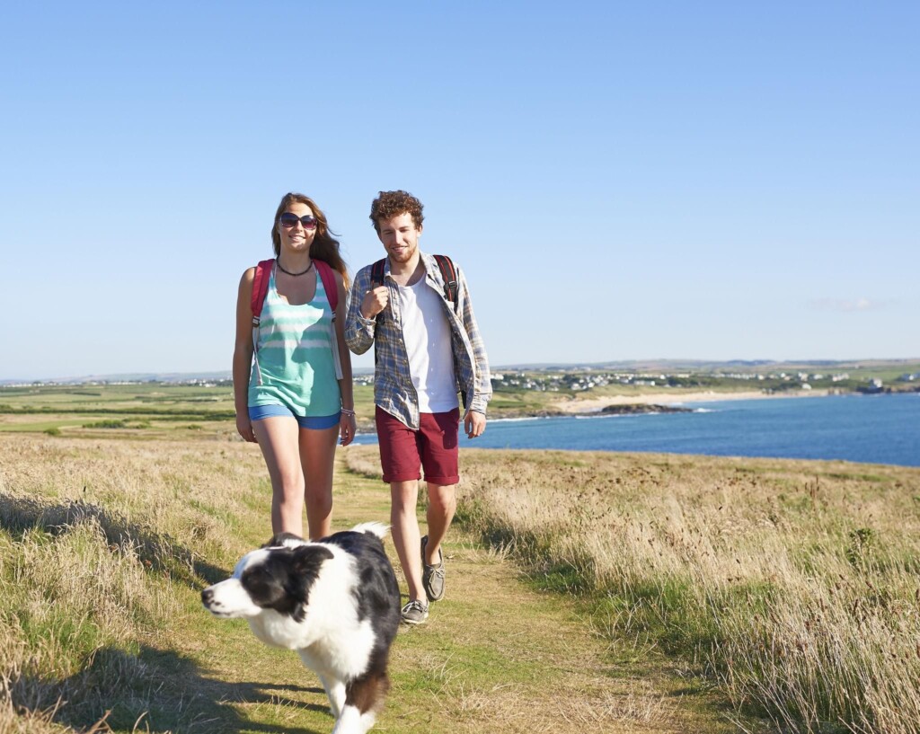 Couple walking with dog along coastal path